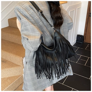 Détail du sac hobo en cuir noir avec bandoulière réglable et franges bohèmes