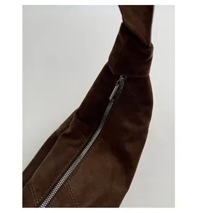 Détail macro de la fermeture éclair en métal argenté sur un sac fourre-tout en daim marron