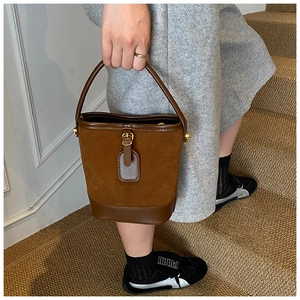 Detailed view of vintage brown suede bucket bag with leather trim and gold hardware