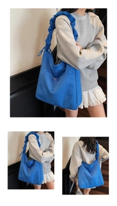 Macro view of blue canvas tote bag featuring stylish ruched handle and brand woven label