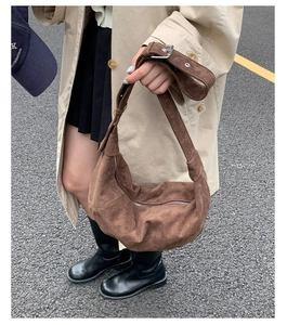 Détail du sac hobo en daim marron foncé avec bandoulière réglable et boucle argentée