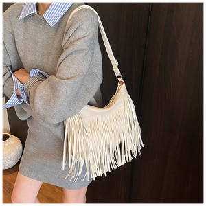 Détail du sac bandoulière croissant beige avec longues franges bohèmes et texture cuir souple