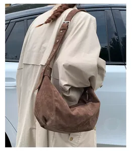 Détail du sac hobo en daim marron avec bandoulière réglable porté par le mannequin