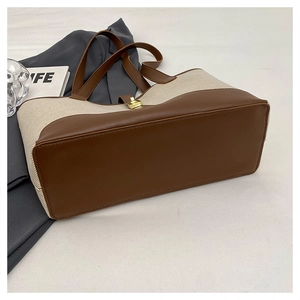 Close-up of contrast stitch canvas tote bag with brown leather base and golden metal buckle
