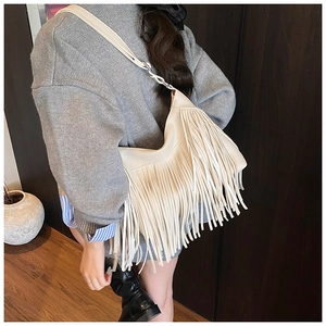 Vue latérale d'un sac hobo beige à franges en cuir texturé au style bohème élégant