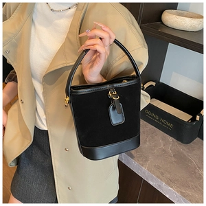 Detail of black bucket bag featuring suede and smooth leather patchwork with gold hardware