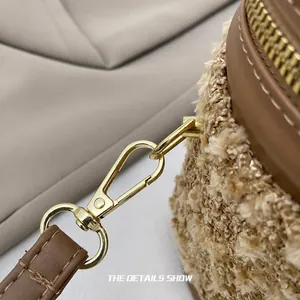 Detail eines hochwertigen Goldkarabiners und braunem Lederbesatz an Plüsch-Beuteltasche