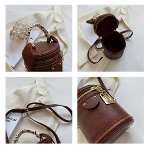 Detail view of vintage brown bucket bag with silk scarf handle and gold hardware accents