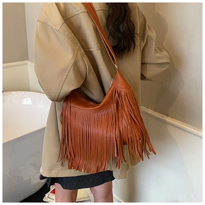 Détail d'un sac bandoulière marron à franges avec texture litchi au style bohème