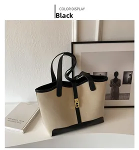 Detail of beige canvas tote bag with black leather trim and elegant gold metal buckle