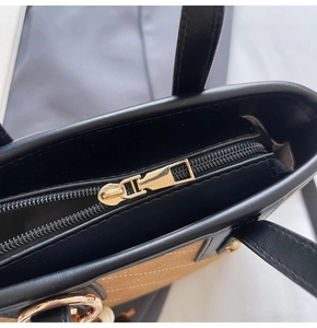 Dettaglio macro delle cuciture e zip dorata su borsa tote nera e beige