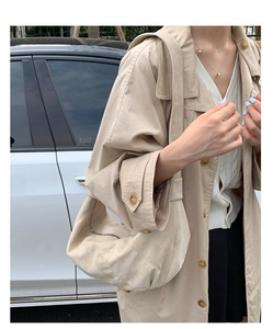 Détail d'un sac hobo en daim beige avec fermeture éclair porté par un mannequin en ville