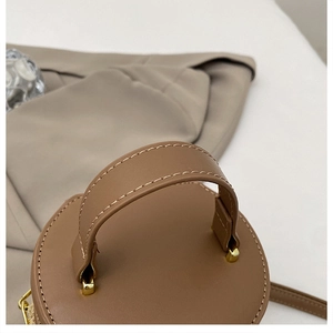 Primer plano de bolso cubo marrón con costuras en contraste y detalles metálicos dorados