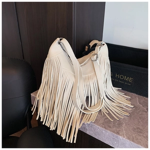 Gros plan détaillé du sac à franges beige avec boucle en métal argenté sur la bandoulière