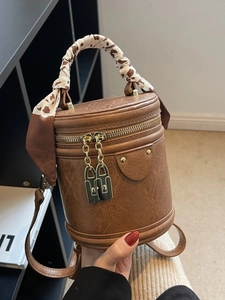 Vintage brown cylindrical bucket bag with cow print scarf handle and gold hardware