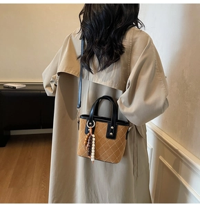 Dettaglio della borsa a secchiello vintage in pelle scamosciata con cuciture e perle