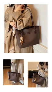 Detail view of coffee brown tote bag with leather texture and stylish beaded tassel charm