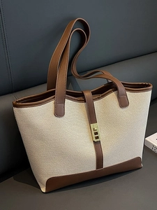 Chic beige canvas and brown leather tote bag with gold metal buckle on a grey bench