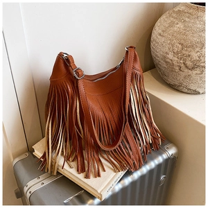 Détail du sac seau en cuir marron avec de longues franges et une fermeture éclair en métal