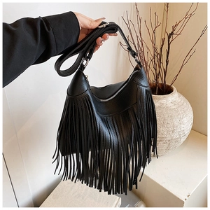 Détail du sac seau noir en cuir grainé avec de longues franges et des boucles argentées