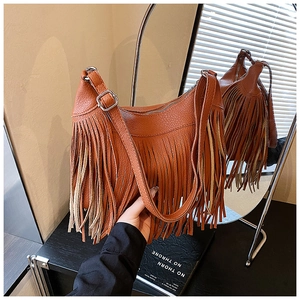 Gros plan sur un sac seau orange rétro avec pompons à franges et texture cuir grainé