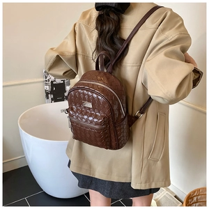 Vue détaillée d'un sac à dos en cuir tressé marron foncé avec fermetures éclair argentées
