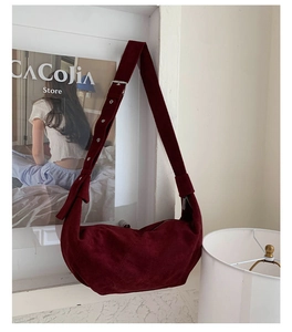 Détail du sac hobo en daim bordeaux avec une large bandoulière réglable et boucle métal