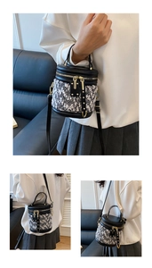 Detailansichten einer schwarz-weißen Tweed-Beuteltasche mit Lederbesatz und Goldzipper