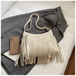 Sac seau chic à franges beige avec bandoulière réglable sur une surface en tissu