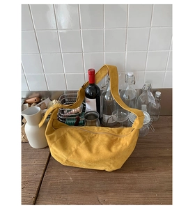 Détail d'un sac demi-lune en daim gingembre sur une table en bois et décor chic
