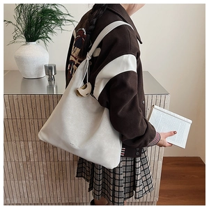 Gros plan d'un grand sac fourre-tout minimaliste en cuir blanc cassé porté à l'épaule