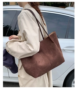 Outdoor shot of large brown suede tote bag featuring slim shoulder straps and minimalist style