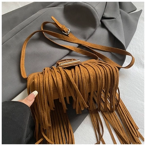 Close-up detail of a brown Maillard-style suede retro saddle bag with long fringe tassels