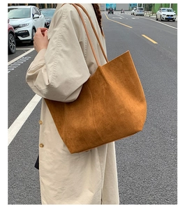 Side view of large brown suede tote bag carried by model on a city street for commuting