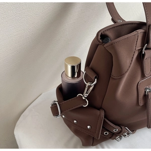 Détail d'une poche latérale de cabas marron café avec clous argentés et boucle métallique