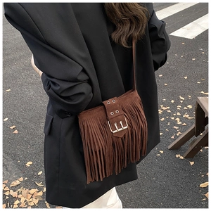 Détail d'un sac bohème en daim marron avec franges denses et boucle métallique décorative