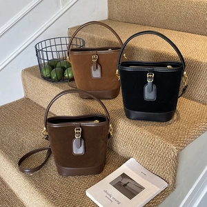 Vintage suede bucket bags in black, dark brown, and tan colors on a creative setup