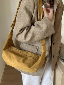 Sac hobo minimaliste en daim jaune moutarde porté avec un blazer marron élégant