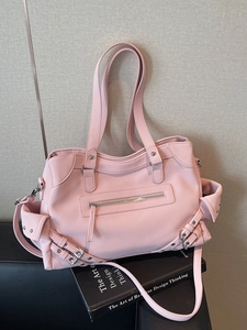 Sac fourre-tout rose à poches multiples avec clous et bandoulière sur un livre