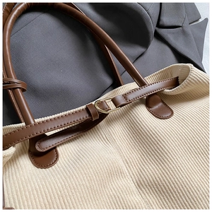 Detailed close-up of corduroy tote bag featuring leather straps and gold metal buckle