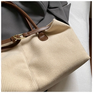 Detail of off-white corduroy tote bag showing soft ribbed texture and brown leather strap