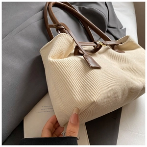 Detailed shot of beige corduroy tote bag showing its soft ribbed texture and leather straps