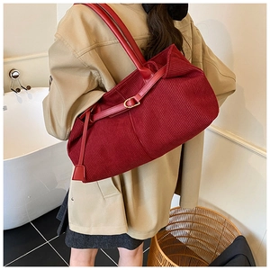 Detail view of burgundy corduroy tote bag with leather straps and golden buckle decoration