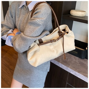 Detail of off-white corduroy texture and brown leather strap on a shoulder bag