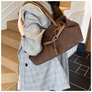Detail of dark brown corduroy tote bag with leather handle and metal buckle adjustment