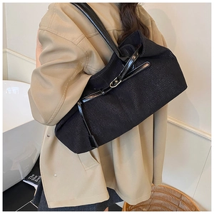 Close-up of black corduroy shoulder bag featuring adjustable leather strap and metal buckle