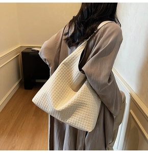 Detail of minimalist woven cream tote bag showing intricate geometric texture and PU material