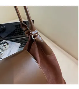 Detail showing high-quality silver metal rings and mixed leather textures on a brown tote