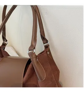 Detail of a brown tote bag featuring mixed textures, silver hardware, and precise stitching