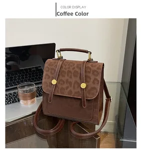Detail eines kaffeebraunen Rucksacks mit Leopardenmuster und goldener Hardware am Tisch